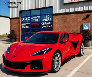 Three-quarter side view of a bright red Chevrolet Corvette Z06 parked in a shop parking space.