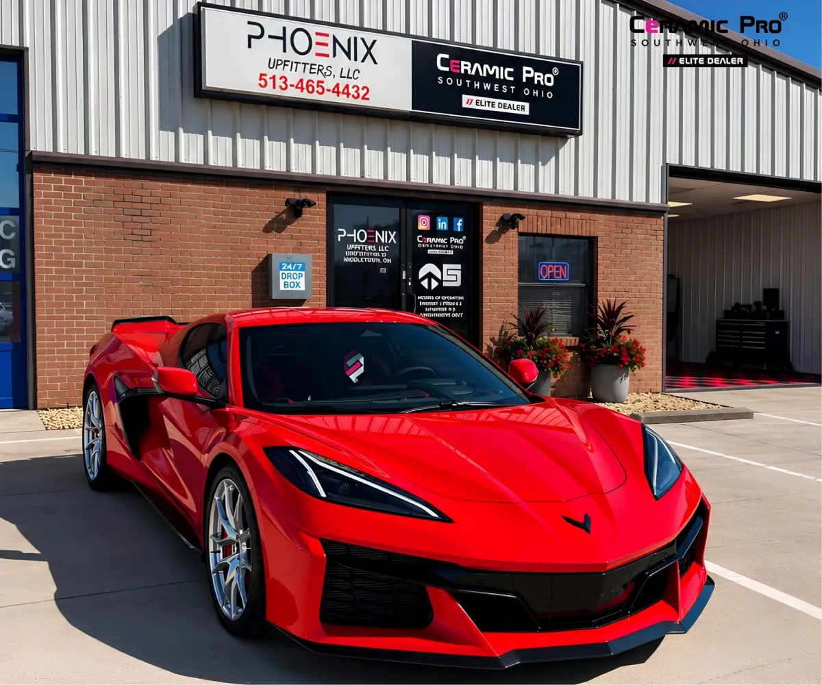 Front angle view of a bright red Chevrolet Corvette Z06 parked outside the Phoenix Upfitters and Ceramic Pro building.